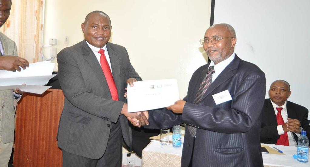 Dr. Gerald Muchemi being presented with a certificate of facilitation of the workshop